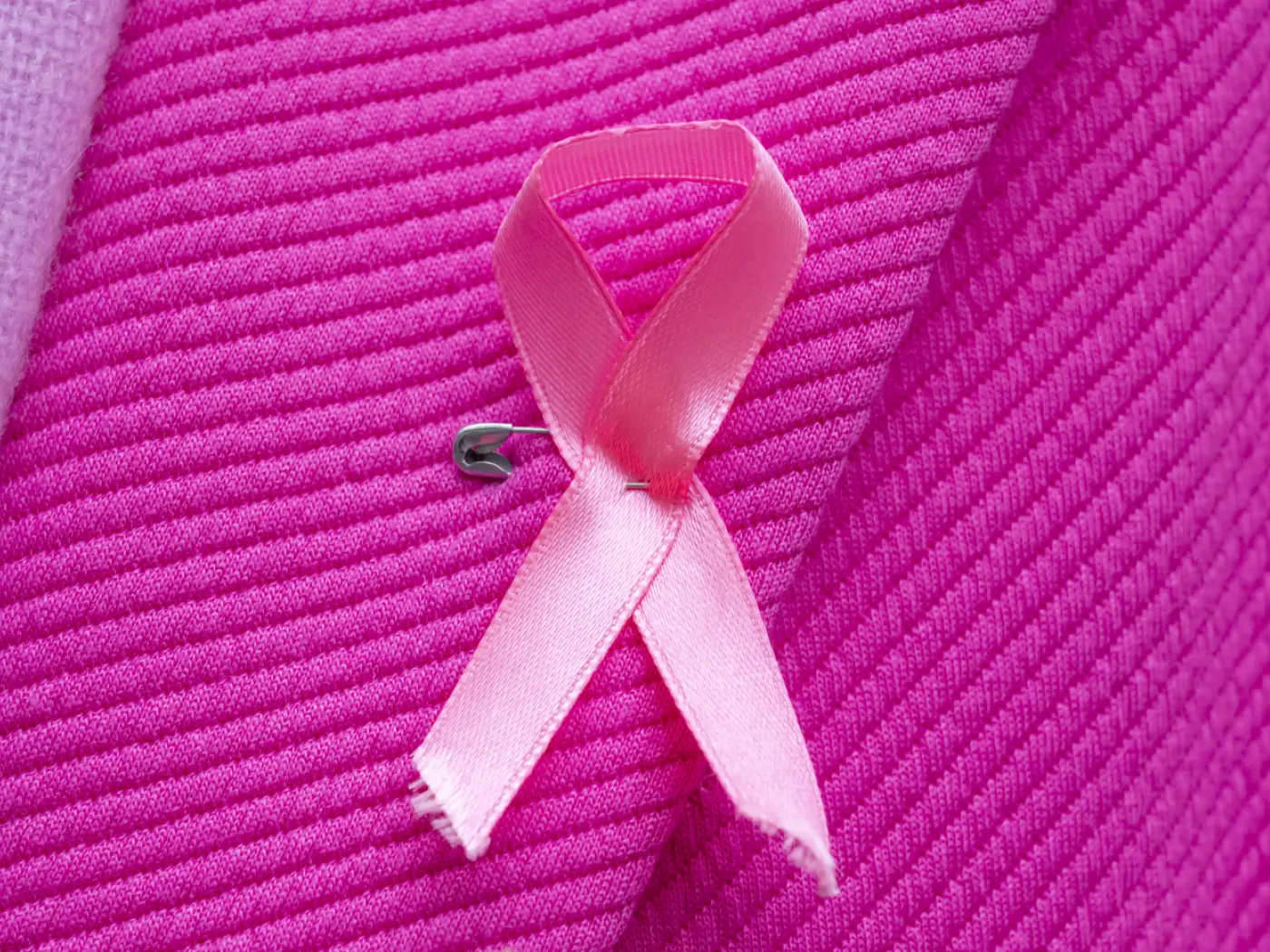 Un nastro rosa applicato a un indumento, fissato con una spilla da balia.