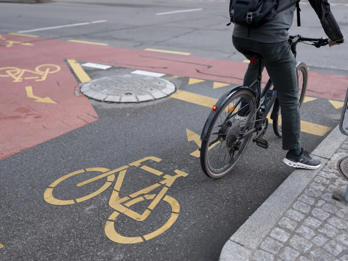 Un ciclista si sta preparando a girare su una pista ciclabile contrassegnata da segnali di traffico gialli.